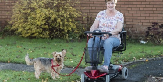 mobility A woman on a mobility scooter with a dog on a lead.