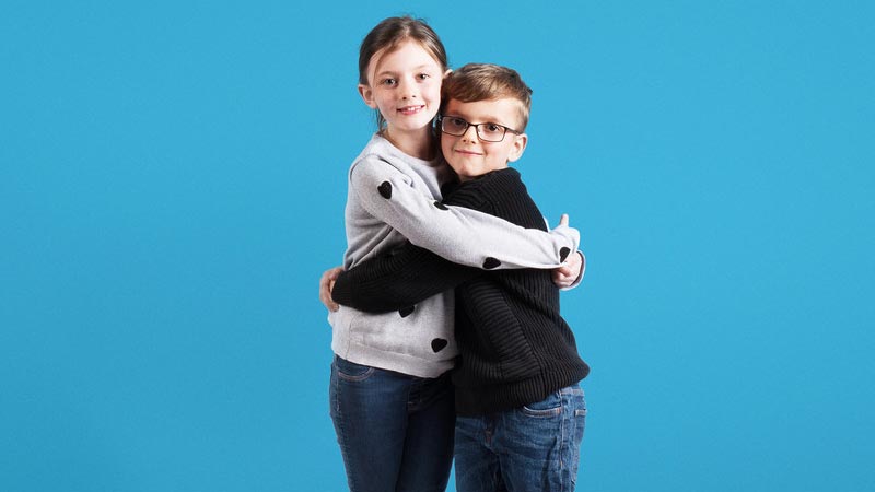 onefamily-junior-isa-blue Young girl and young boy hugging