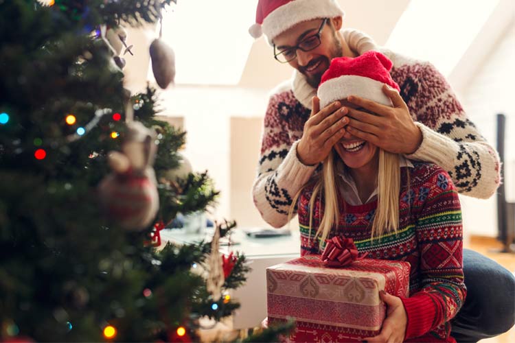a young couple stand in front of a christmas tree the man is standing behind - Best Christmas Traditions a young couple stand in front of a christmas tree the man is standing behind - Best Christmas Traditions