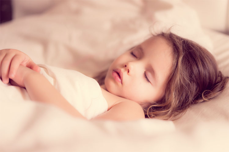 A little girl asleep on white sheets.