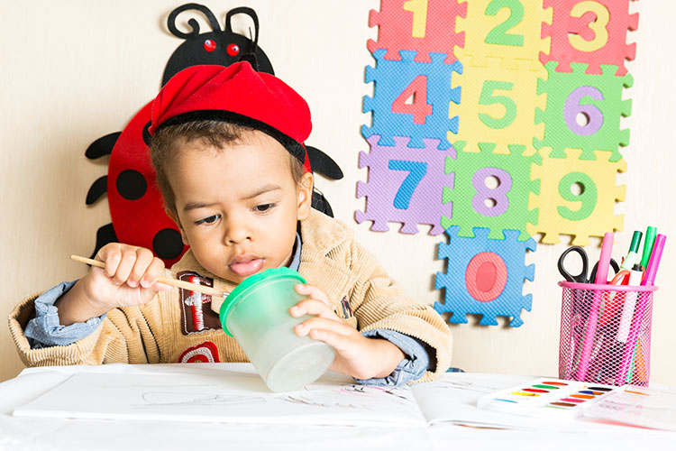 A child playing with a jar and pens, with numbers in the background.