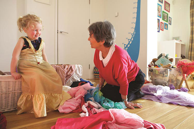 A grandmother and daughter playing dress-up amongst a pile of clothes.