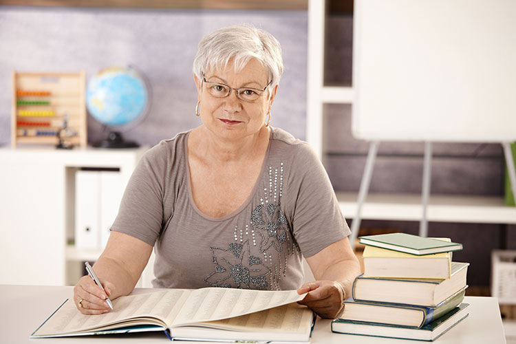 Older woman working through a large ledger.
