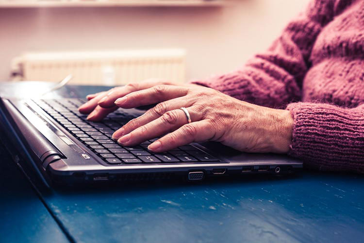Close-up of hands on a laptop keyboard.