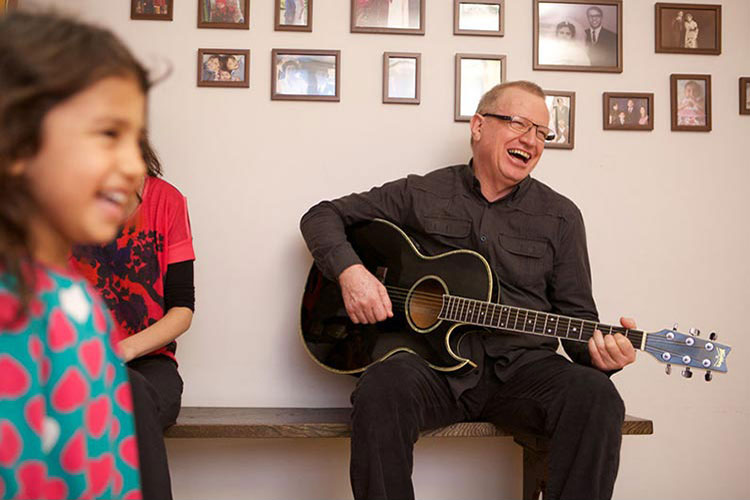 A man playing guitar for his grandchildren.